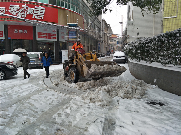 巿环卫局工作人员开铲车在八一路铲除路面积雪