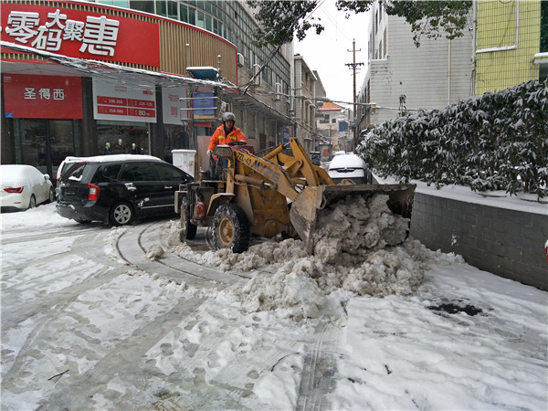 巿环卫局工作人员开铲车在八一路铲除路面积雪