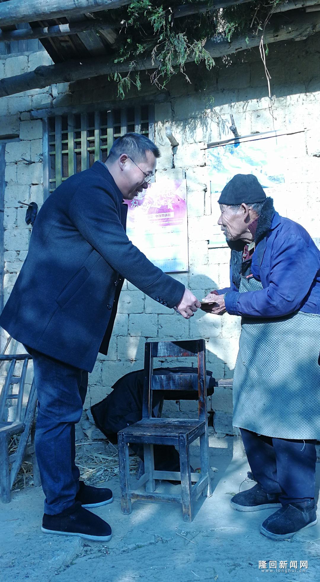 图为县住房公积金主任王化武为贫困户送去慰问金
